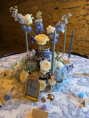 Centre de table de mariage classique avec vase en céramique bleue et blanche, roses crème et hortensias bleus.