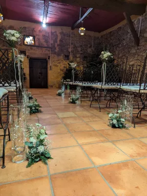 Allée de cérémonie décorée de guirlandes de sapin, chrysanthèmes blancs, eucalyptus et vases lumineux, mariage classique.