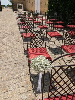 Décoration d'allée de cérémonie champêtre avec grappes de gypsophile et rubans blancs sur les chaises.