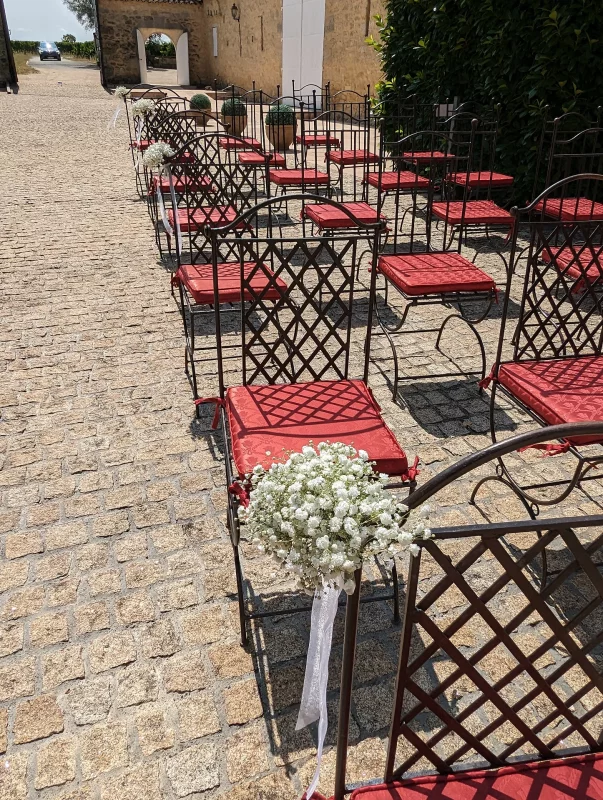 Countryside ceremony aisle decoration with clusters of gypsophila and white ribbons adorning the chairs