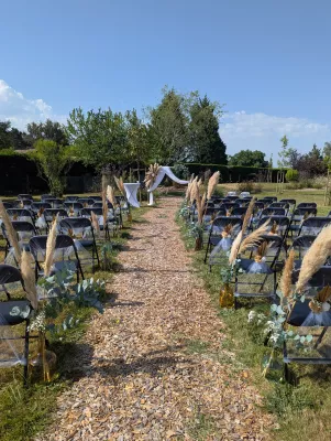 Bohemian botanical wedding ceremony aisle dressed with pampas grass and eucalyptus on the chairs and a floral arch.