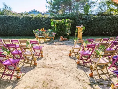 Ambiance de cérémonie de mariage exotique avec une arche florale tropicale, des ananas dorés et des chaises colorées.