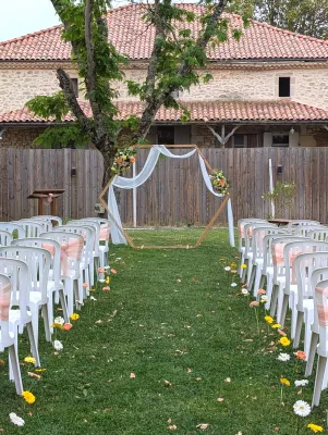 Cérémonie de mariage champêtre sophistiquée avec arche florale et allée de gerberas colorés.