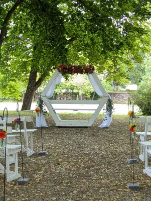 Allée de cérémonie avec arche florale et petits bouquets suspendus au Domaine de Valmont.