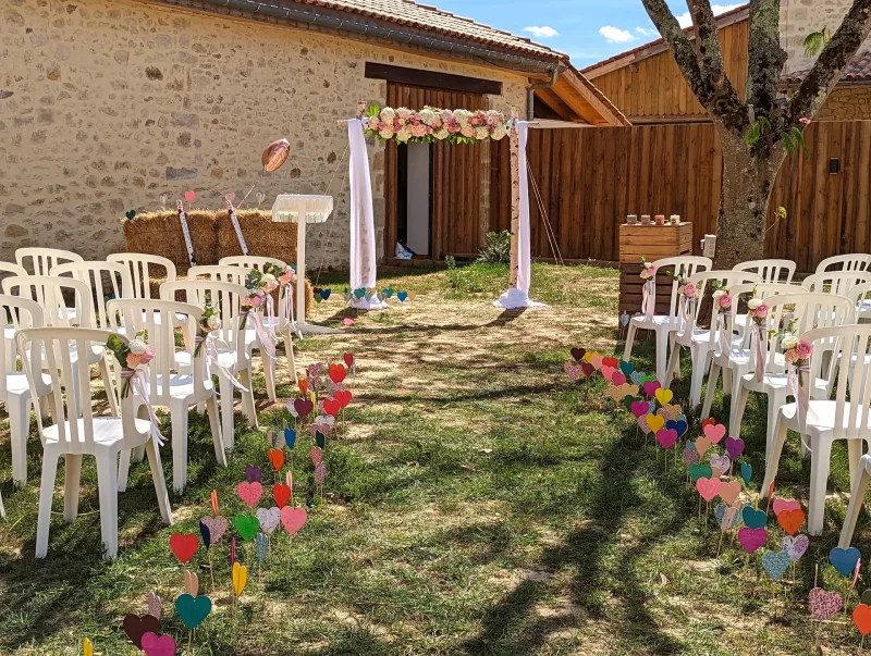 Elegant countryside outdoor ceremony styling with a floral arch, decorated chairs and a colourful aisle.