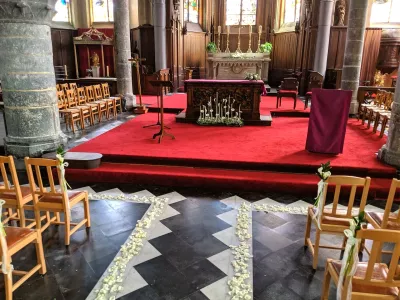 Vue d'ensemble de la décoration de cérémonie de mariage classique, avec pétales de roses blanches et petits arums sur les chaises.