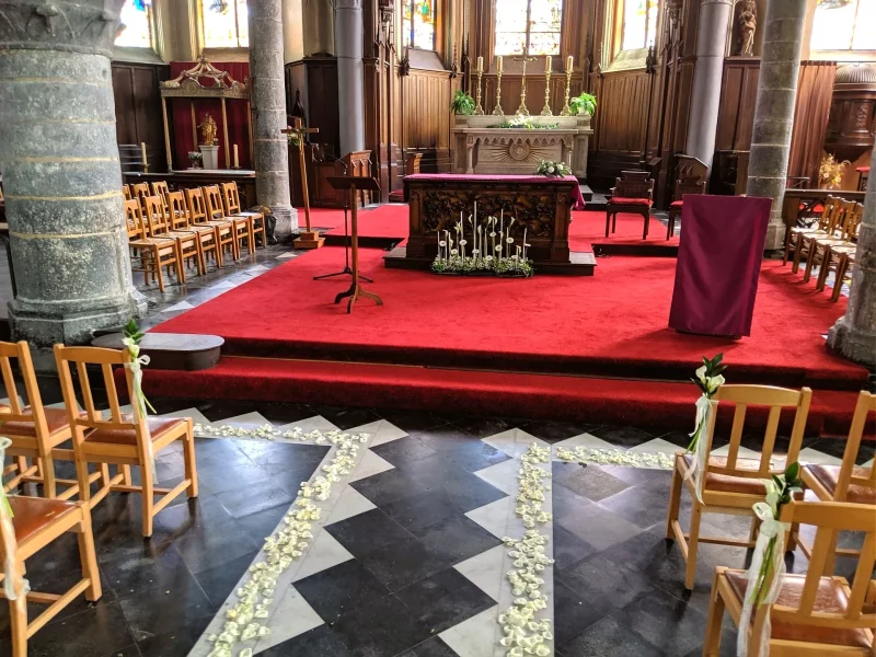 Vue d'ensemble de la décoration de cérémonie de mariage classique, avec pétales de roses blanches et petits arums sur les chaises.