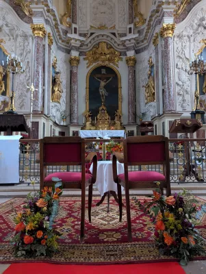 Opulent floral decoration for church ceremony with orange roses, dried flowers, and burgundy foliage.