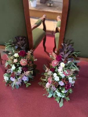 Sophisticated rustic floral arrangements with burgundy roses and pink carnations for ceremony