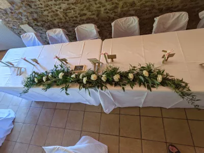 Chemin de table floral champêtre avec roses blanches et abondant feuillage d'eucalyptus pour la table d'honneur d'un mariage.