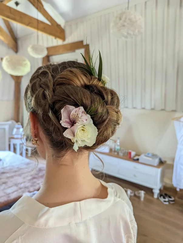 Coiffure de mariée bohème avec alstroemeria rose et petite rose blanche, agrémentée de graminées vertes