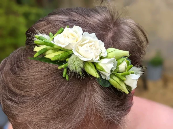 Peigne fleuri champêtre pour coiffure de mariage, avec des roses blanches, freesias et graminées, élégant et frais.