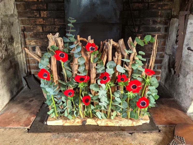 A rustic-chic and elegant photo corner for a winter wedding, featuring vibrant red anemones and eucalyptus foliage.