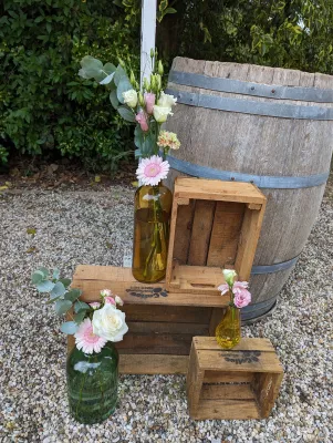 Arrangement floral champêtre pour photobooth avec roses, gerbera et eucalyptus, sur des caisses en bois.