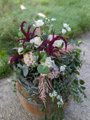 Décoration florale champêtre sur tonneau avec eucalyptus, roses blanches et amarante pour un mariage
