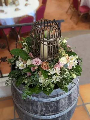 Colonne décorative champêtre avec un arrangement floral de roses, œillets, eucalyptus et une lanterne en métal.