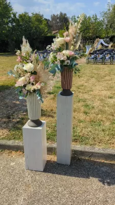 Decorative floral columns with white and pink roses, eucalyptus and pampas grass for a country wedding ceremony.