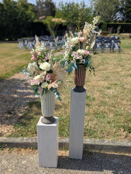 Floral columns with white and pink roses, eucalyptus and pampas grass for a country wedding ceremony.