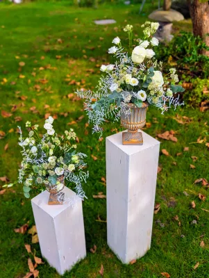 Two classic floral arrangements on columns, with white roses and lisianthus, eucalyptus and frosted foliage for an autumn wedding.