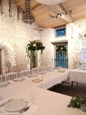 Gros plan sur les majestueuses colonnes florales dorées, ornées de roses blanches et d'eucalyptus luxuriant, encadrant l'espace repas pour un mariage champêtre moderne.