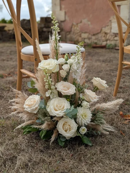 Composition florale d'allée de mariage bohème avec roses crème, dahlias, pampa et eucalyptus.