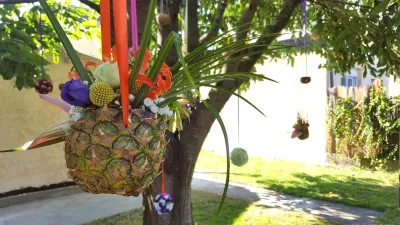 Composition florale suspendue avec ananas, gloriosa orange, eustoma violet et feuillage, créant une ambiance exotique et festive.
