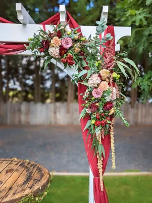 Décoration florale de mariage pour arche avec roses, hortensias, et feuillage vert frais, créant une ambiance champêtre et romantique.