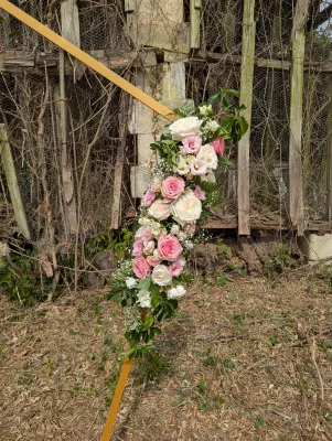 Détail d'une composition florale pour arche de mariage, avec roses blanches, roses pâles et gypsophile, style champêtre.