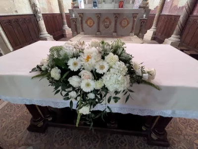 Grande composition florale blanche pour l'autel d'une église, avec hortensias, roses et gerberas, style classique et élégant.