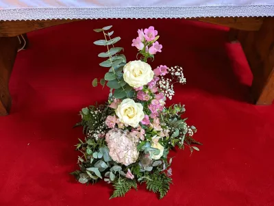 Grande composition florale de cérémonie style champêtre avec roses crème, hortensias roses, muflier fuchsia et eucalyptus.