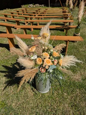 Composition florale boheme pour ceremonie de mariage, avec roses peche et pampas, sur un seau galvanise. Ambiance naturelle.