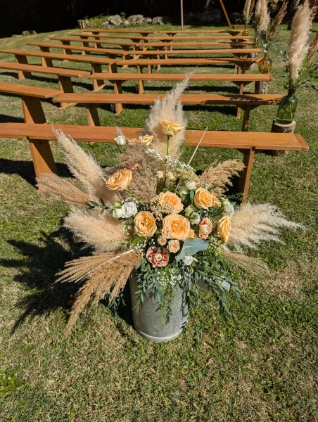 Composition florale boheme pour ceremonie de mariage, avec roses peche et pampas, sur un seau galvanise. Ambiance naturelle.