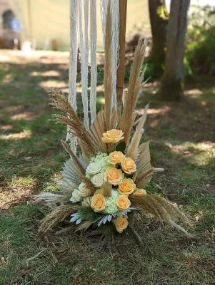 Composition florale boheme pour ceremonie, avec roses peche, fleurs creme et herbes de la pampa vaporeuses.