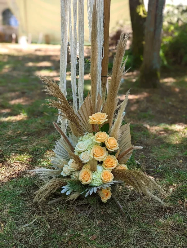 Composition florale boheme pour ceremonie, avec roses peche, fleurs creme et herbes de la pampa vaporeuses.