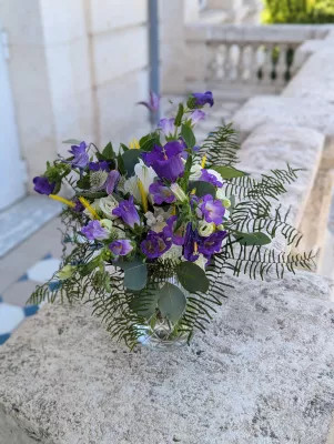 Lush bohemian floral arrangement featuring purple campanulas, white roses and ferns for a wedding.