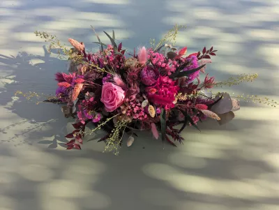 Composition florale horizontale champêtre sophistiquée avec dahlias fuchsia, roses et feuillages pour mariage.