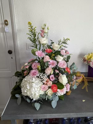 Grande composition florale champêtre avec hortensia blanc, roses, gerberas et eucalyptus pour mariage.