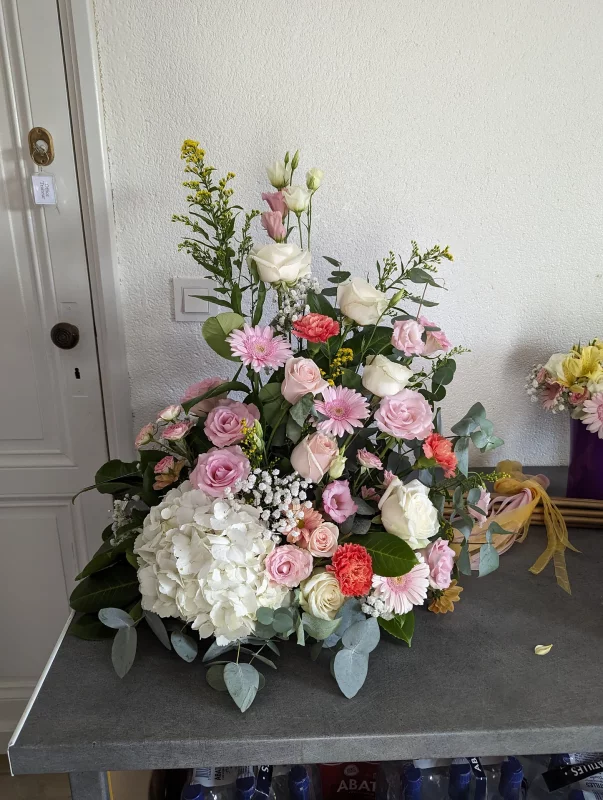 Grande composition florale champêtre avec hortensia blanc, roses, gerberas et eucalyptus pour mariage.