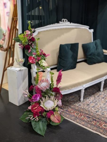 Grande composition florale exotique avec proteas, anthuriums, roses et feuillages luxuriants, style audacieux.