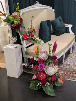 Arrangement floral impressionnant avec grandes proteas, roses et anthuriums, feuillage tropical, pour une décoration exotique chic.