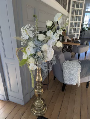 Large romantic organic floral arrangement with white roses, anthuriums, and hydrangeas on a golden column, Château des Eyres.