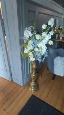 Large romantic organic floral arrangement with white roses, anthuriums, and hydrangeas on a golden column, Château des Eyres.