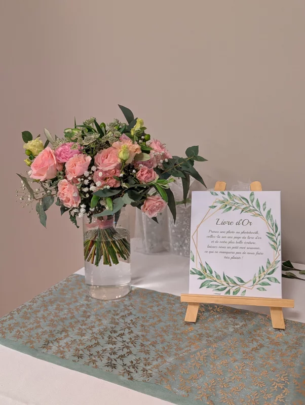 Composition florale champêtre sophistiquée avec roses et eucalyptus, près d'un livre d'or.