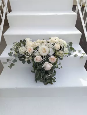 Sophisticated country-style floral arrangement with roses, hydrangeas, and gypsophila on steps.
