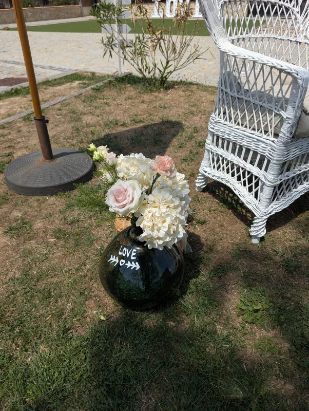 Sophisticated country floral arrangement with roses, hydrangeas, and carnations in a glass vase.