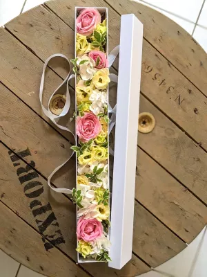 Elongated wedding floral arrangement featuring roses, lisianthus, and hydrangeas in a modern white box.