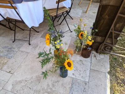 Compositions florales champêtres avec tournesols et chardons en vases vintage pour un mariage.