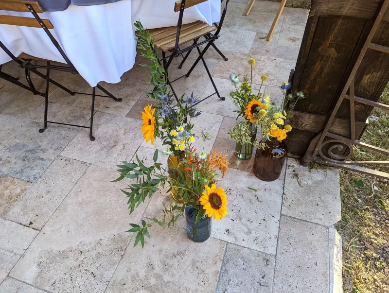 Compositions florales champêtres avec tournesols et chardons en vases vintage pour un mariage.