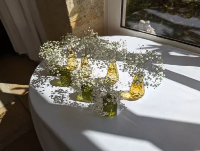 Composition de table champêtre avec gypsophile dans des mini-vases en verre vert et jaune.