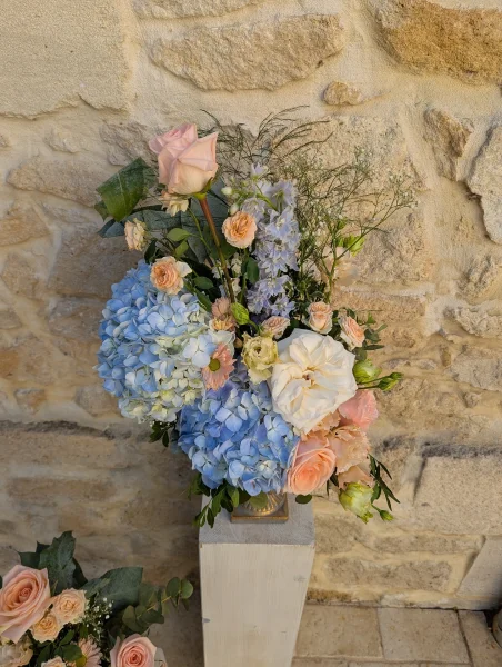 Grande composition florale champêtre pour mariage, avec hortensias bleus, roses pâles et feuillage frais à Barsac.